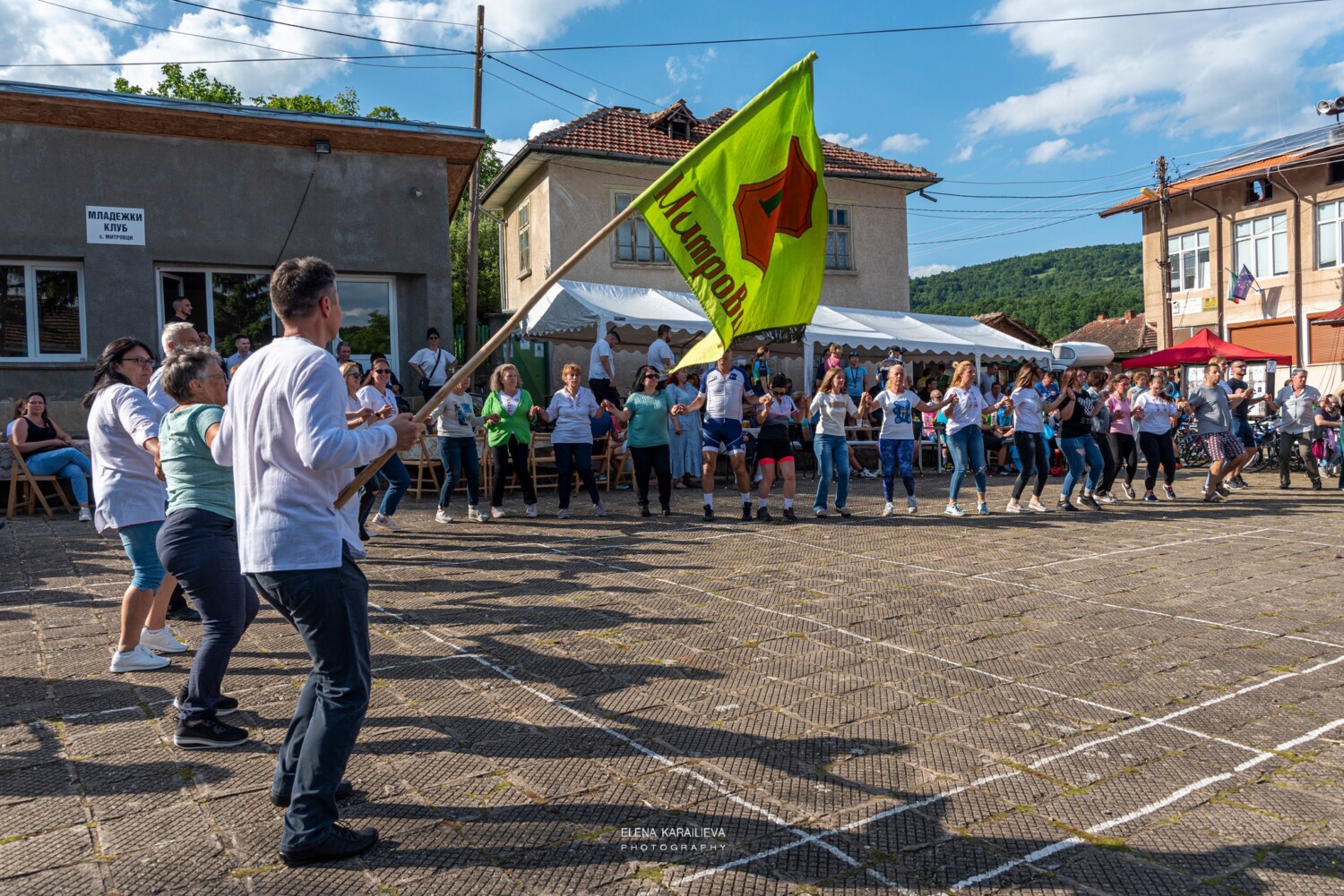Местните жители и колоездачи играят хоро в село Митровци на финала на велообиколката на Северозапада
